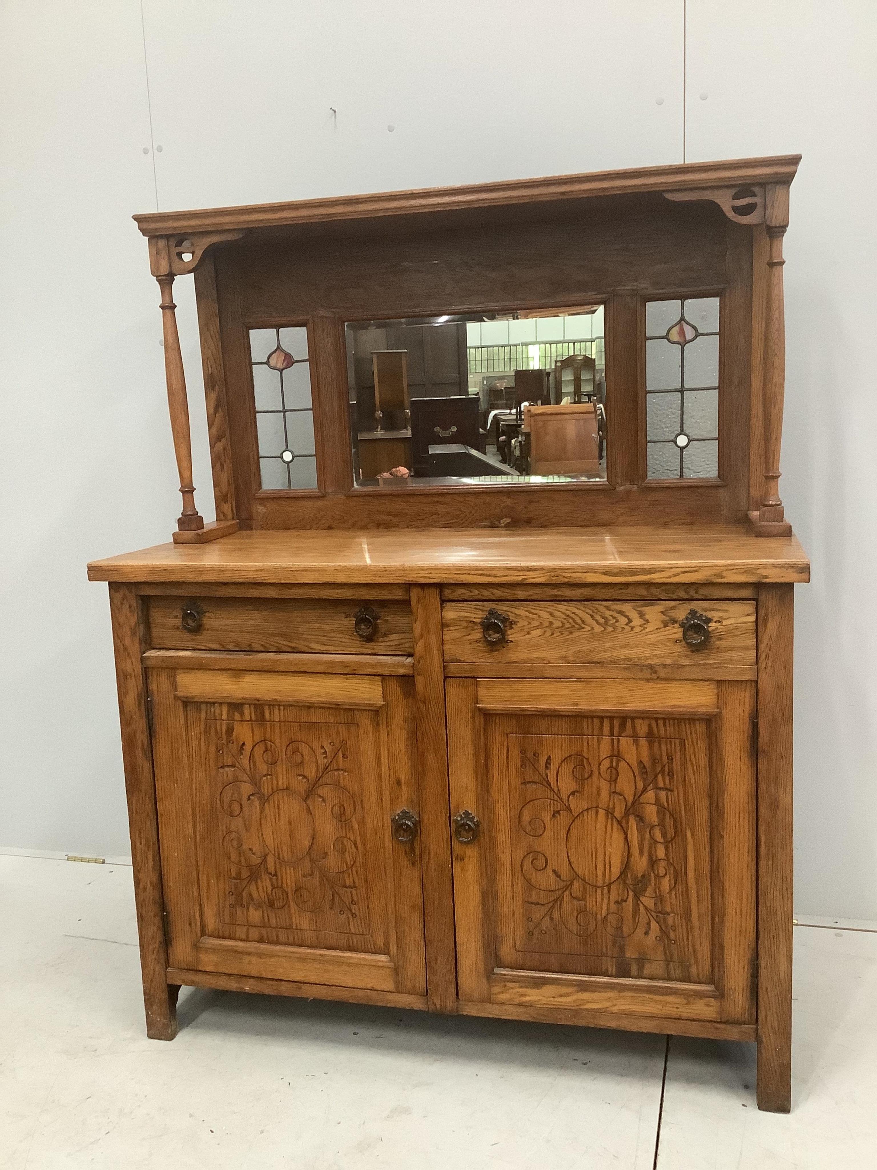 An Arts and Crafts oak sideboard, with stained glass raised mirrored back, width 122cm, depth 48cm, height 155cm. Condition - fair